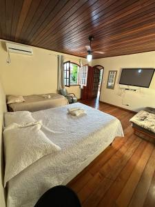 a bedroom with a large bed and a flat screen tv at Villa Palmeiras Suítes in Cabo Frio