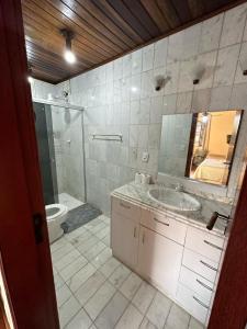a bathroom with a sink and a toilet and a mirror at Villa Palmeiras Suítes in Cabo Frio