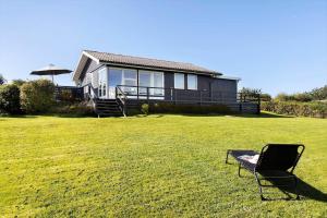 a chair sitting in the grass in front of a house at LF14058-Roslev-Eskovvej-58 in Flovtrup +11 photos