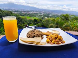 a plate of food and a glass of orange juice at Hotel Mirador Mayday Mountain View in Alajuela City