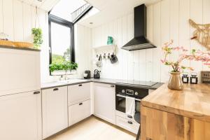 a kitchen with white cabinets and a stove at Onder het dak van Brabant in Mierlo +29 photos