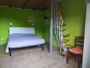 a bedroom with green walls and a bed and a staircase at La Coccinella in Canale Monterano