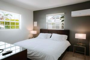 a bedroom with a white bed with two windows at Casa del Sol, 2-Bedroom Home Near Palm Beach in Noord