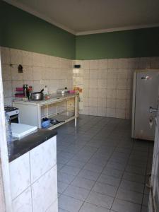 una cucina con pareti verdi e pavimento piastrellato di Alojamento Maceió a Maceió