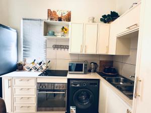 a small kitchen with a washer and a microwave at 2Bed in exquisite golf estate! in Roodepoort