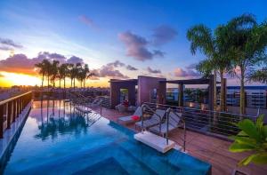 a swimming pool on top of a building with a sunset at Studio 818 no edf. TIME, Ponta Verde in Maceió