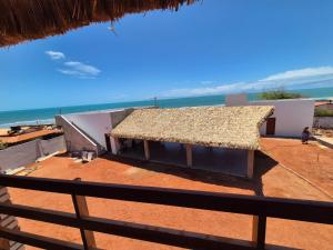 a building with a straw roof next to the ocean at Pousada Vista do Pôr do Sol in Areia Branca