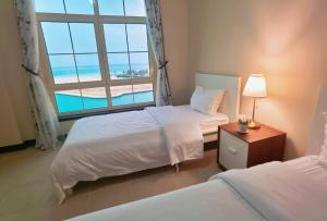 Un dormitorio con dos camas y una gran ventana. en شقة منتزة المارينا, en King Abdullah Economic City