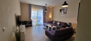 Sala de estar con sofás morados y TV en شقة منتزة المارينا, en King Abdullah Economic City