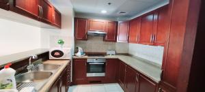 Una pequeña cocina con gabinetes de madera y un fregadero. en شقة منتزة المارينا, en King Abdullah Economic City
