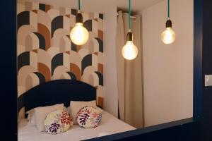 a bedroom with two pillows on a bed with three lights at Rouen - Studio indépendant avec cour in Rouen