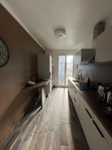 a kitchen with white cabinets and a wooden floor at UNESCO Le Havre Appartement 100m2 in Le Havre