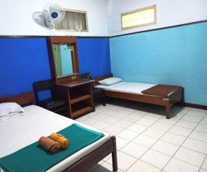 a room with two beds and a blue wall at Hotel Budi Famili Budget Syariah in Ciamis +9 photos