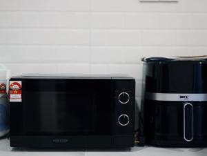 a black microwave sitting next to a black appliance at 30 PAX Perling Party House #Miao Nalisa# in Johor Bahru