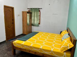 a bedroom with a bed with a yellow comforter at 2BHK Farm Villa In Kovai Kuttralam Mainroad Near ISHA By Shivalaya in Coimbatore