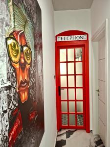 eine rote Tür und eine Wand mit einem Gemälde eines Kopfes in der Unterkunft fruit tower in Thessaloniki