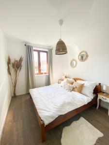 a bedroom with a bed with white sheets and a window at Berkenye Vendégház Tisza-tó in Abádszalók