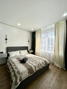 a bedroom with a bed and a large window at Arena Park apartments in Almaty
