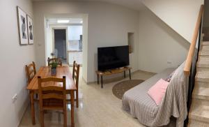 Sala de estar con mesa, cama y TV en Casa Alan, en Burriana