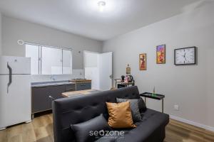 a living room with a black couch and a kitchen at Conforto e Comodidade no Centro de Itajaí - CARs in Itajaí