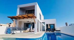 a villa with a swimming pool and a house at Beachfront White Villa in Playa Blanca in Zihuatanejo