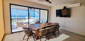 a dining room with a table and chairs and a balcony at Beachfront White Villa in Playa Blanca in Zihuatanejo