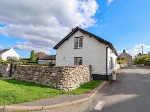 uma casa branca com uma parede de pedra ao lado de uma rua em Cwtch em Cilcain