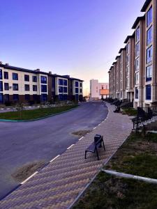 una calle vacía con un banco al lado de un edificio en Квартира посуточно в элитном ЖК, en Zhezdi