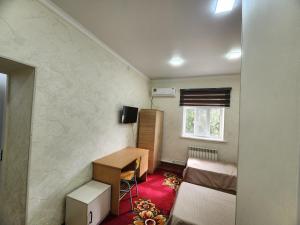 Habitación pequeña con escritorio y cama en Kamila-House, en Urganch
