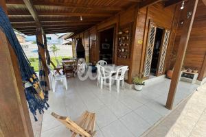 Casa Aconchegante – A 200m da praia da Pinheira في بينيرا: شرفة منزل مع طاولة وكراسي