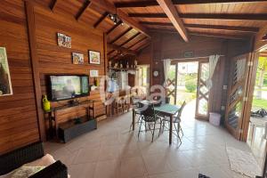 Casa Aconchegante – A 200m da praia da Pinheira في بينيرا: غرفة معيشة مع تلفزيون وطاولة وكراسي