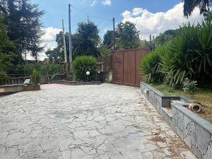 ein Hinterhof mit einer Steinterrasse mit einem Holzzaun in der Unterkunft Ciury's Etna Holidays in Trecastagni