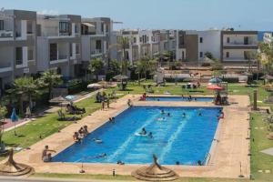 Una gran piscina con gente en un resort. en Mansouria 1BR Pool View Beach Parking, en Minaret de Mansuria