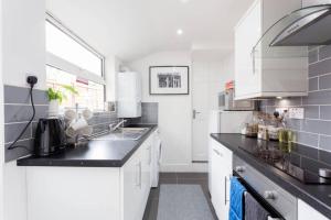 a kitchen with white cabinets and black counter tops at Ashton House in Luton