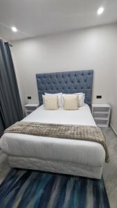 une chambre avec un grand lit avec une tête de lit bleue dans l'établissement Ket Apartments 3 - Modern, Secure, Comfortable & Free WiFi, à Lusaka