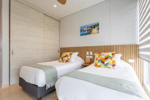 two beds in a room with white walls at New! 3BR Ocean View apt at Calablanca B6 in Pendales +29 photos