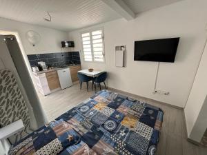 a bedroom with a bed and a kitchen with a table at Le Camélia - Résidence Terre et Truffes in Le Lamentin