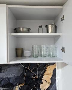 a cupboard with bowls and other kitchen utensils at Garage y Patio Privado en Salta Casa Completa in Salta