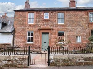 an old brick house with a gate and a door at Milford in Great Corby