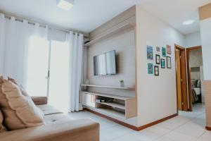 a living room with a couch and a tv on a wall at Apto Aconchegante em Jardim Camburi in Camburi