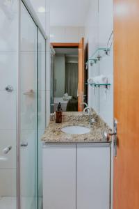 a bathroom with a sink and a glass shower at Apto Aconchegante em Jardim Camburi in Camburi