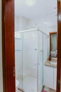 a bathroom with a glass shower with a toilet at Apto Aconchegante em Jardim Camburi in Camburi