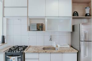 a white kitchen with a stove and a sink at Apto Aconchegante em Jardim Camburi in Camburi +15 photos