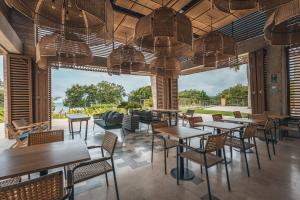 Un restaurante con mesas y sillas y un gran ventanal. en 4BR Seaview Apartment at Calablanca D5, en Pendales