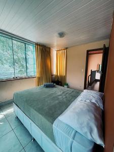 a bedroom with a large bed in front of two windows at Poente Hostel in Belo Horizonte