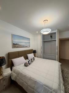a bedroom with a large white bed with a chandelier at Real Homes 2 bedroom Nova Apartments in Accra