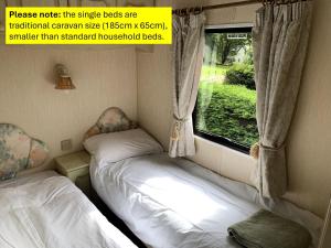 two beds in a small room with a window at Osprey Caravan in Onich