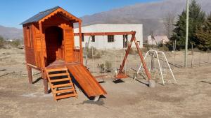 a wooden play house with a ladder and a swing at Cabañas Inti Huasi in Tafí del Valle