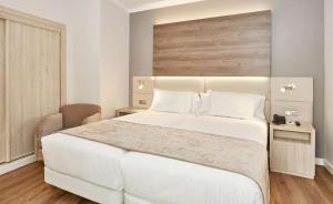 a bedroom with a large white bed with white pillows at NH Córdoba Califa in Córdoba