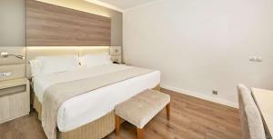 a bedroom with a large bed and a chair at NH Córdoba Califa in Córdoba